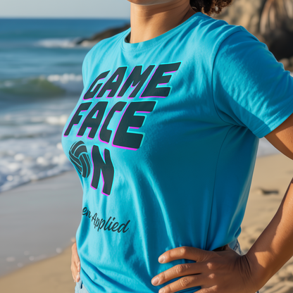 Person wearing a blue 'Game Face On, Sunscreen Applied' t-shirt on a beach